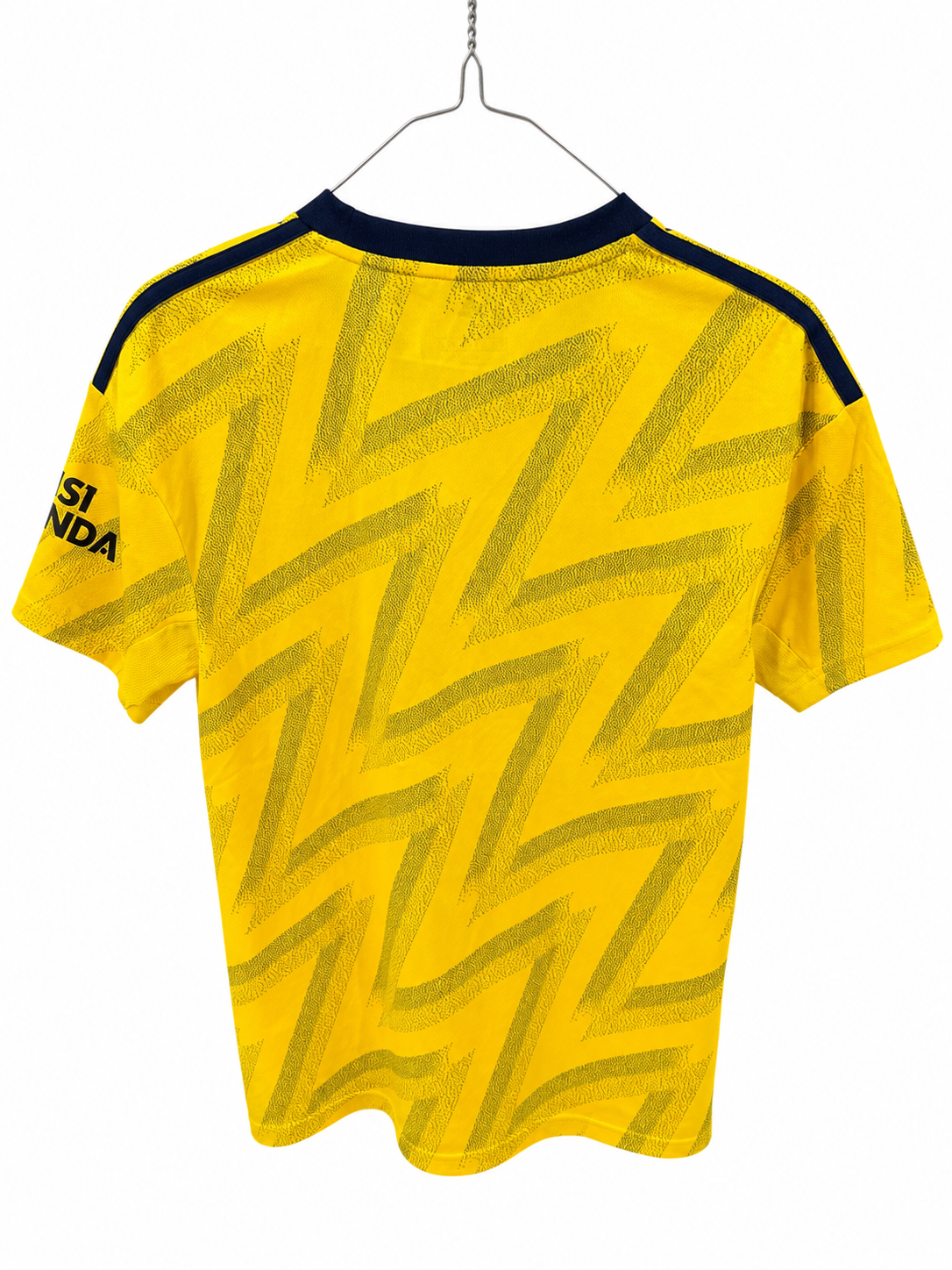 Yellow short-sleeve soccer jersey with a dark navy patterned zigzag design, hanging on a metal hanger against a white background.
