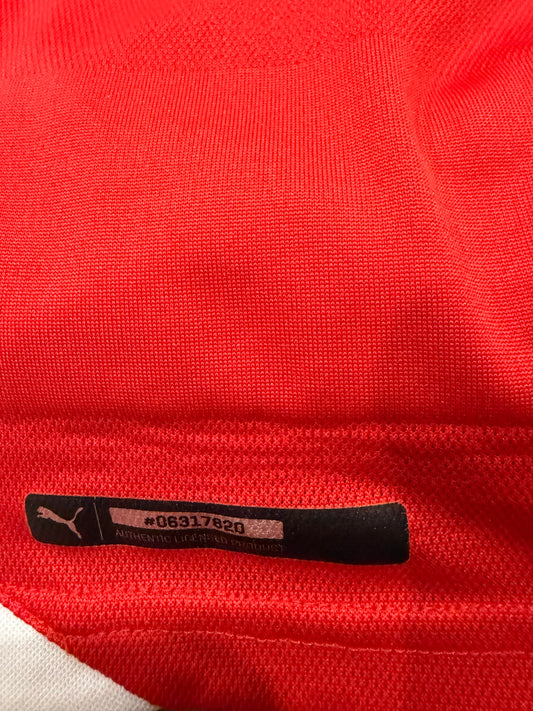 Close-up of a red Puma athletic jersey showing the black Puma logo tag with size and garment code information.