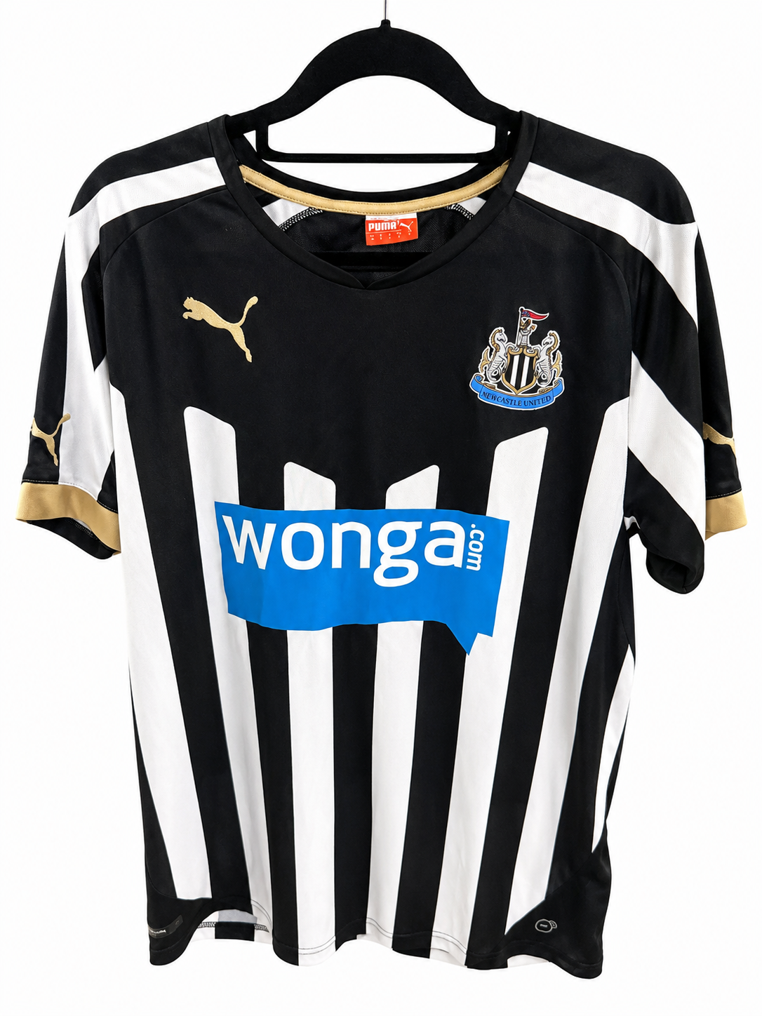 A black and white striped Puma Newcastle United soccer jersey with gold accents, featuring the 'wonga.com' sponsor logo on the front, hanging on a black hanger against a white background.